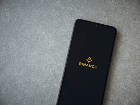 Lod, Israel - July 16,2023: Binance app launch screen on smartphone on ceramic stone background. Top view flat lay with copy space.
