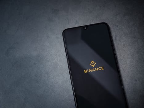 Lod, Israel - July 16,2023: Binance app launch screen on smartphone on dark marble stone background. Top view flat lay with copy space.
