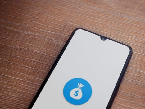 Lod, Israel - July 16,2023: Spender app launch screen on smartphone on wooden background. Top view flat lay with copy space.