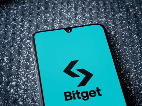 Lod, Israel - July 16,2023: Bitget app launch screen on smartphone on metallic background. Close up top view flat lay.