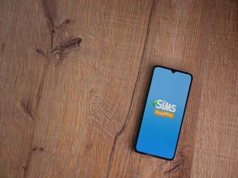 Lod, Israel - July 16,2023: The Sims FreePlay app launch screen on smartphone on wooden background. Top view flat lay with copy space.