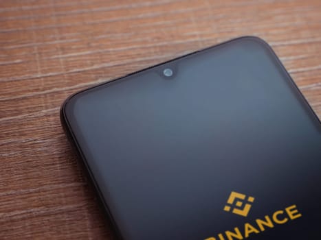 Lod, Israel - July 16,2023: Binance app launch screen on smartphone on wooden background. Top view flat lay with copy space.