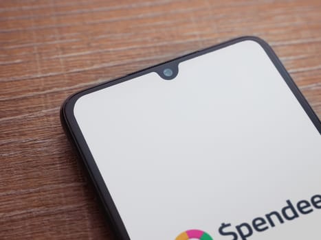 Lod, Israel - July 16,2023: Spendee app launch screen on smartphone on wooden background. Top view flat lay with copy space.