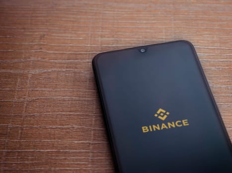 Lod, Israel - July 16,2023: Binance app launch screen on smartphone on wooden background. Top view flat lay with copy space.