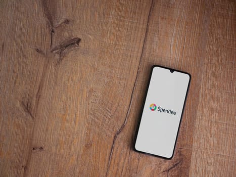 Lod, Israel - July 16,2023: Spendee app launch screen on smartphone on wooden background. Top view flat lay with copy space.