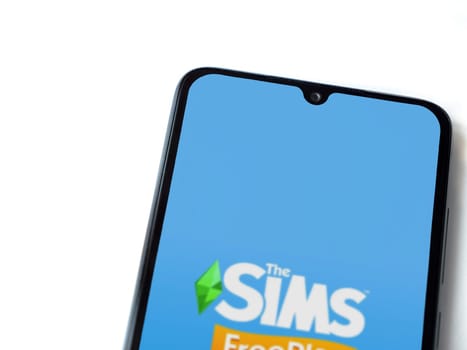 Lod, Israel - July 16,2023: The Sims FreePlay app launch screen on smartphone on white background. Top view flat lay with copy space.
