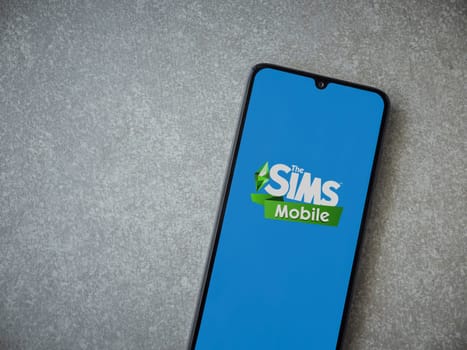 Lod, Israel - July 16,2023: The Sims Mobile app launch screen on smartphone on ceramic stone background. Top view flat lay with copy space.