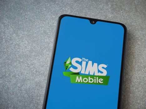 Lod, Israel - July 16,2023: The Sims Mobile app launch screen on smartphone on ceramic stone background. Top view flat lay with copy space.