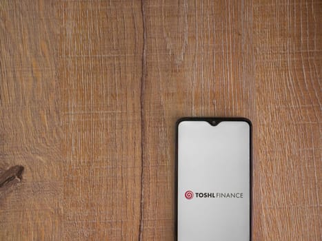 Lod, Israel - July 16,2023: Toshl Finance app launch screen on smartphone on wooden background. Top view flat lay with copy space.