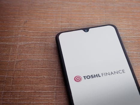 Lod, Israel - July 16,2023: Toshl Finance app launch screen on smartphone on wooden background. Top view flat lay with copy space.