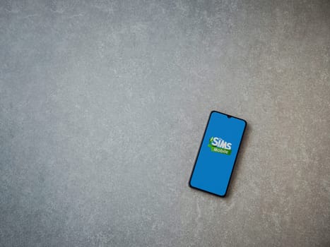 Lod, Israel - July 16,2023: The Sims Mobile app launch screen on smartphone on ceramic stone background. Top view flat lay with copy space.