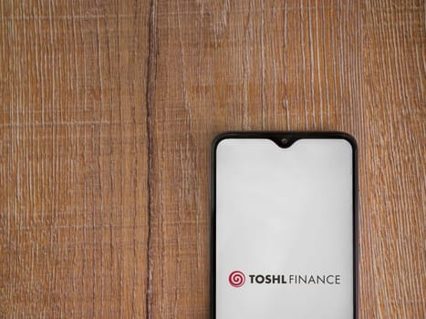 Lod, Israel - July 16,2023: Toshl Finance app launch screen on smartphone on wooden background. Top view flat lay with copy space.