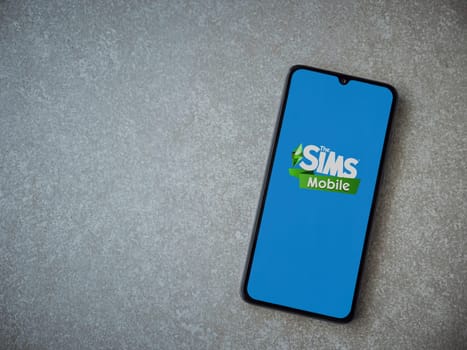 Lod, Israel - July 16,2023: The Sims Mobile app launch screen on smartphone on ceramic stone background. Top view flat lay with copy space.