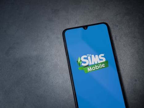 Lod, Israel - July 16,2023: The Sims Mobile app launch screen on smartphone on dark marble stone background. Top view flat lay with copy space.