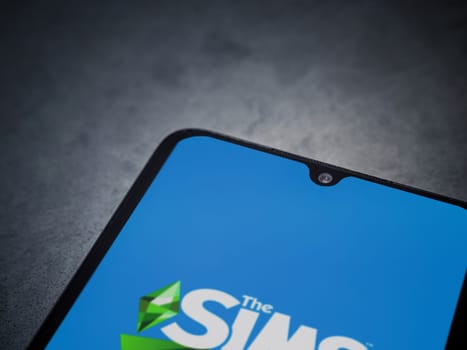 Lod, Israel - July 16,2023: The Sims Mobile app launch screen on smartphone on dark marble stone background. Top view flat lay with copy space.
