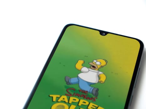 Lod, Israel - July 16,2023: The Simpsons Tapped Out app launch screen on smartphone on white background. Top view flat lay with copy space.