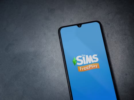 Lod, Israel - July 16,2023: The Sims FreePlay app launch screen on smartphone on dark marble stone background. Top view flat lay with copy space.