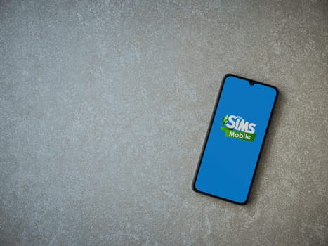 Lod, Israel - July 16,2023: The Sims Mobile app launch screen on smartphone on ceramic stone background. Top view flat lay with copy space.