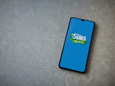 Lod, Israel - July 16,2023: The Sims Mobile app launch screen on smartphone on ceramic stone background. Top view flat lay with copy space.