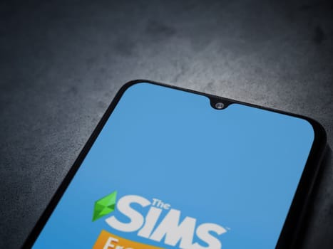 Lod, Israel - July 16,2023: The Sims FreePlay app launch screen on smartphone on dark marble stone background. Top view flat lay with copy space.