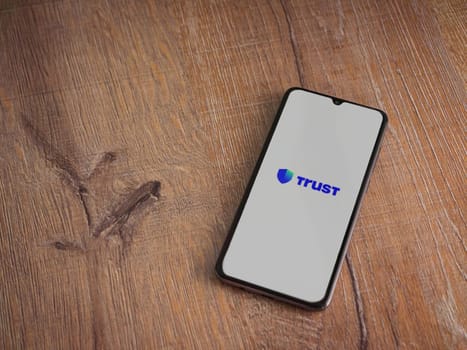 Lod, Israel - July 16,2023: Trust Wallet app launch screen on smartphone on wooden background. Top view flat lay with copy space.