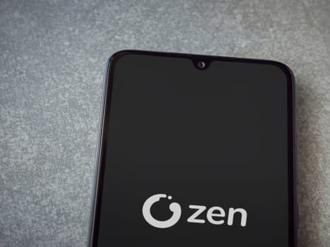 Lod, Israel - July 16,2023: ZEN.COM app launch screen on smartphone on ceramic stone background. Top view flat lay with copy space.