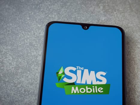 Lod, Israel - July 16,2023: The Sims Mobile app launch screen on smartphone on ceramic stone background. Top view flat lay with copy space.