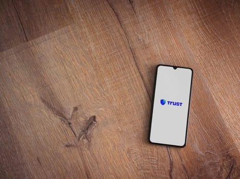 Lod, Israel - July 16,2023: Trust Wallet app launch screen on smartphone on wooden background. Top view flat lay with copy space.