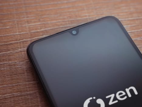 Lod, Israel - July 16,2023: ZEN.COM app launch screen on smartphone on wooden background. Top view flat lay with copy space.