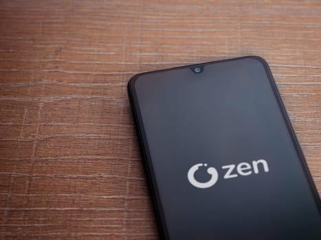 Lod, Israel - July 16,2023: ZEN.COM app launch screen on smartphone on wooden background. Top view flat lay with copy space.