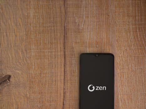 Lod, Israel - July 16,2023: ZEN.COM app launch screen on smartphone on wooden background. Top view flat lay with copy space.
