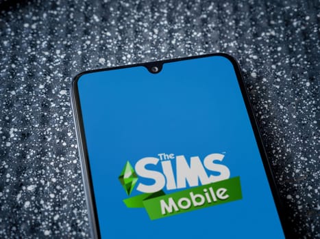 Lod, Israel - July 16,2023: The Sims Mobile app launch screen on smartphone on metallic background. Close up top view flat lay.