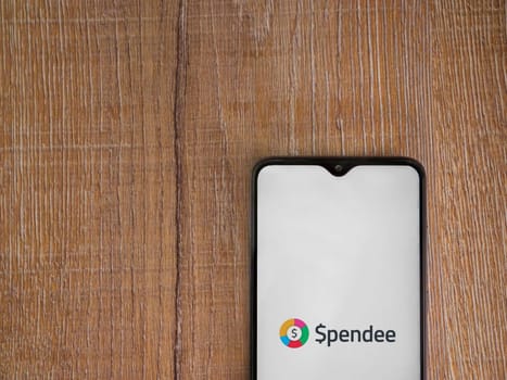 Lod, Israel - July 16,2023: Spendee app launch screen on smartphone on wooden background. Top view flat lay with copy space.