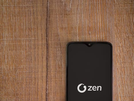 Lod, Israel - July 16,2023: ZEN.COM app launch screen on smartphone on wooden background. Top view flat lay with copy space.