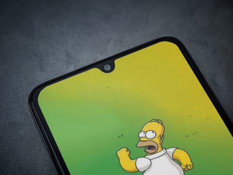 Lod, Israel - July 16,2023: The Simpsons Tapped Out app launch screen on smartphone on dark marble stone background. Top view flat lay with copy space.
