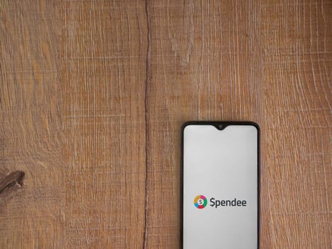 Lod, Israel - July 16,2023: Spendee app launch screen on smartphone on wooden background. Top view flat lay with copy space.