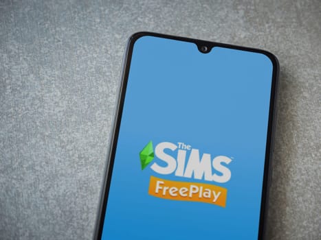 Lod, Israel - July 16,2023: The Sims FreePlay app launch screen on smartphone on ceramic stone background. Top view flat lay with copy space.