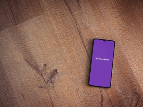 Lod, Israel - July 16,2023: WorldRemit app launch screen on smartphone on wooden background. Top view flat lay with copy space.