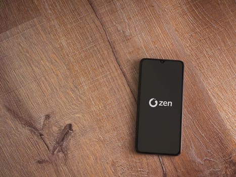 Lod, Israel - July 16,2023: ZEN.COM app launch screen on smartphone on wooden background. Top view flat lay with copy space.