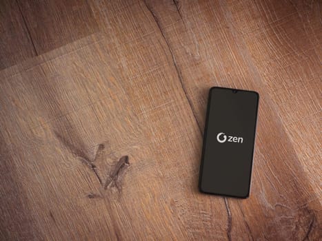 Lod, Israel - July 16,2023: ZEN.COM app launch screen on smartphone on wooden background. Top view flat lay with copy space.