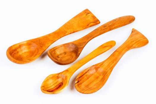 Handmade crafted wooden spoons as kitchen utensils in different shapes on white background.