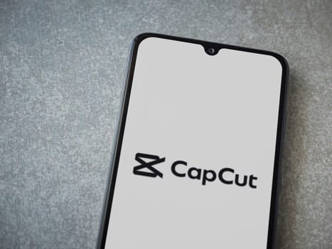 Lod, Israel - July 16,2023: CapCut app launch screen on smartphone on ceramic stone background.. Top view flat lay with copy space.