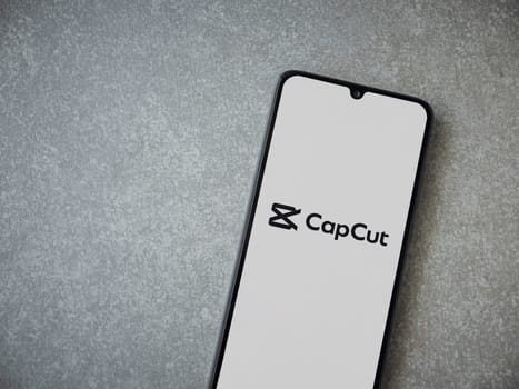Lod, Israel - July 16,2023: CapCut app launch screen on smartphone on ceramic stone background.. Top view flat lay with copy space.