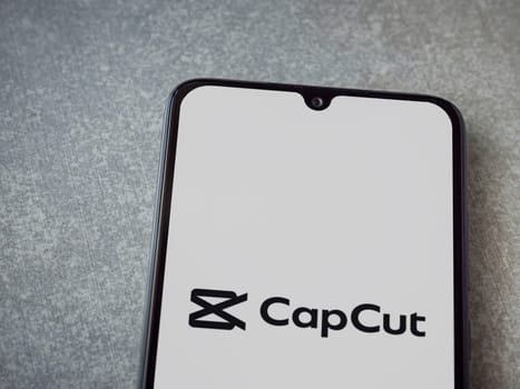 Lod, Israel - July 16,2023: CapCut app launch screen on smartphone on ceramic stone background.. Top view flat lay with copy space.