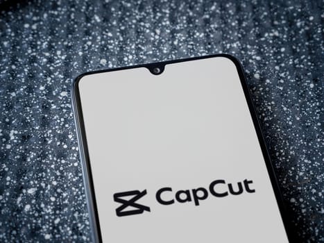 Lod, Israel - July 16,2023: CapCut app launch screen on smartphone on metallic background. Close up top view flat lay.