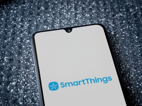 Lod, Israel - July 16,2023: Smartthings app launch screen on smartphone on metallic background. Close up top view flat lay.