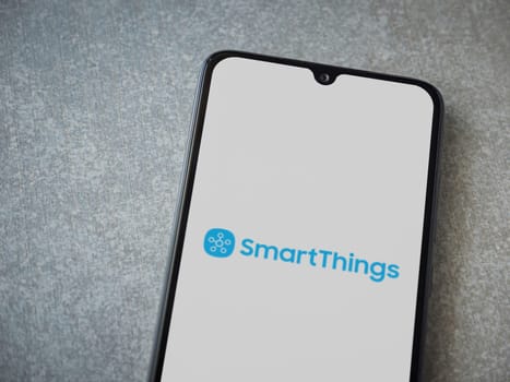 Lod, Israel - July 16,2023: Smartthings app launch screen on smartphone on ceramic stone background. Top view flat lay with copy space.