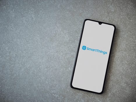 Lod, Israel - July 16,2023: Smartthings app launch screen on smartphone on ceramic stone background. Top view flat lay with copy space.