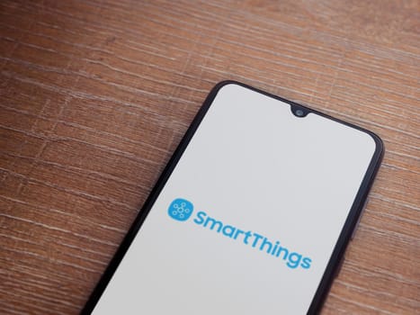 Lod, Israel - July 16,2023: Smartthings app launch screen on smartphone on wooden background. Top view flat lay with copy space.