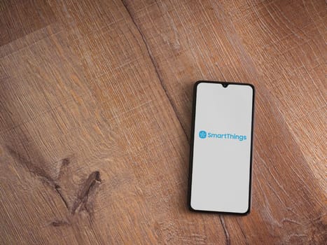 Lod, Israel - July 16,2023: Smartthings app launch screen on smartphone on wooden background. Top view flat lay with copy space.